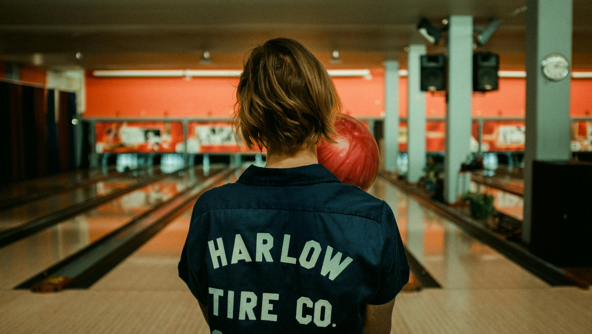 person-holding-a-bowling-ball-at-a-bowling-alley-viewed-from-behind