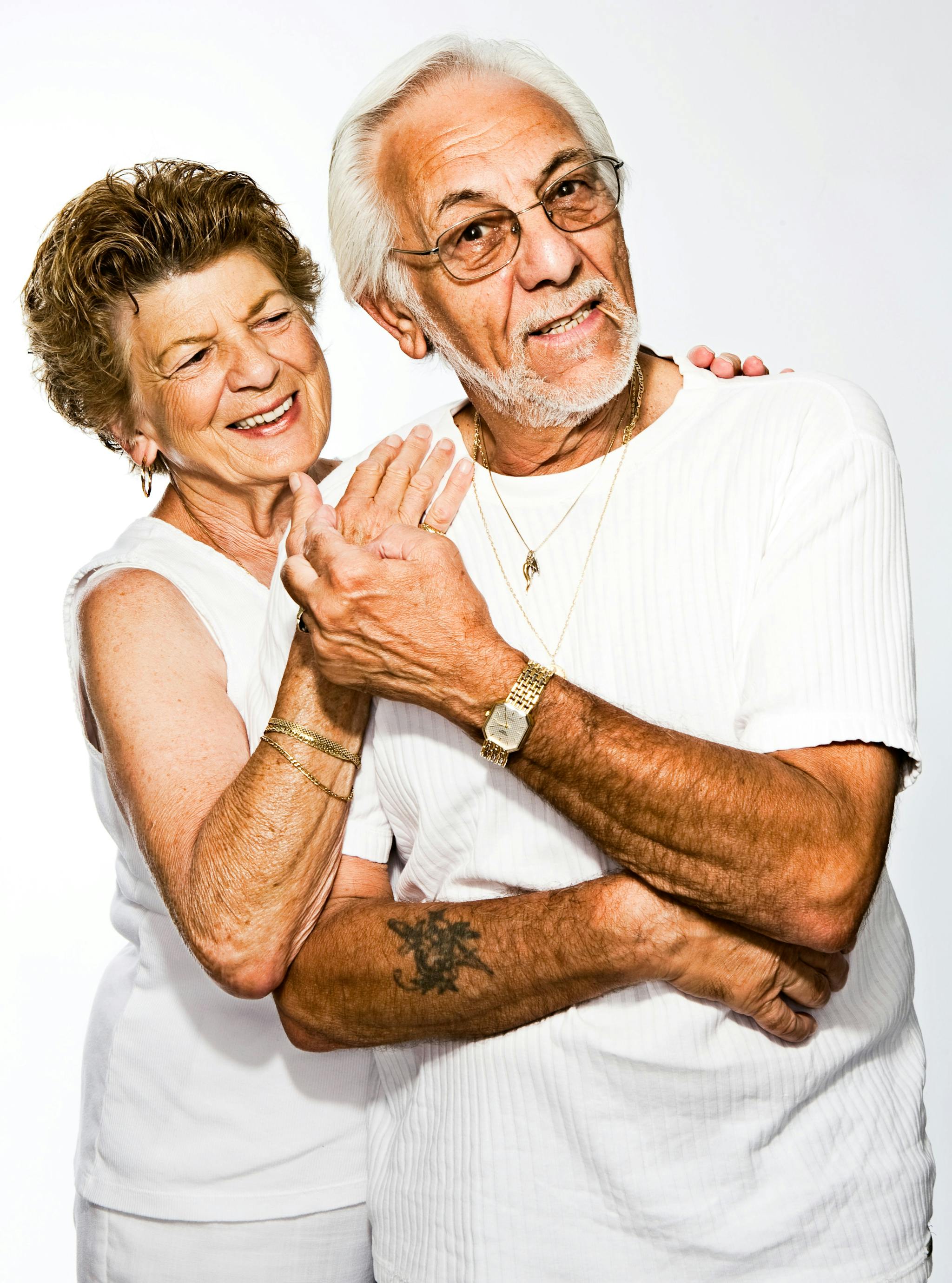elderly-couple-hugging-and-smiling-against-a-white-background